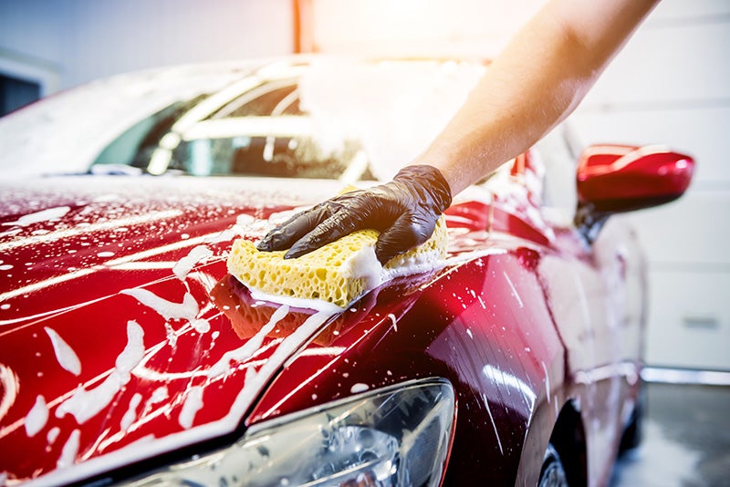 A person washing a red car